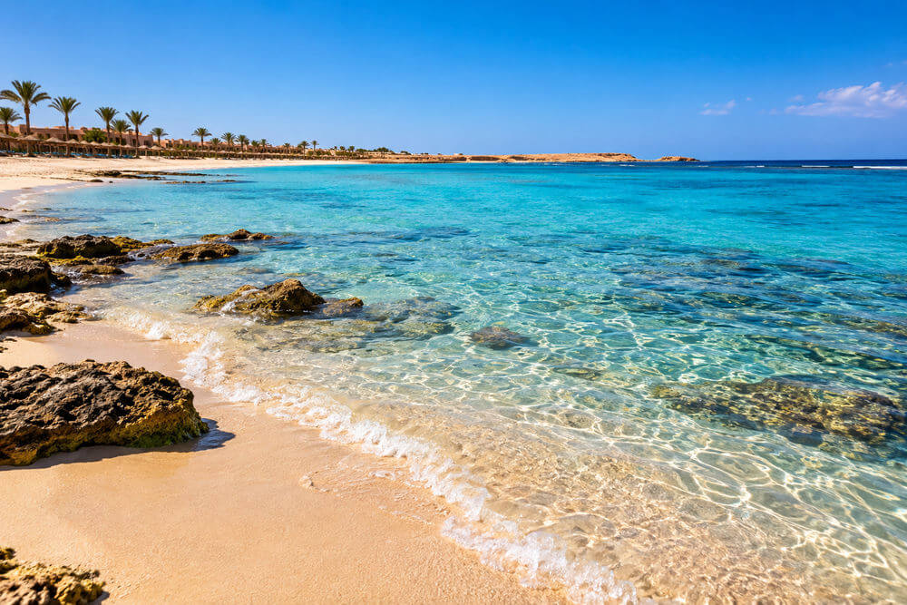 Piaszczysty fragment zatoki z hotelami na wybrzeżu Marsa Alam
