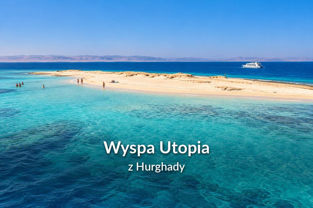 Piaszczysta wyspa otoczona turkusowymi wodami Morza Czerwonego, z turystami na plaży i łodzią wycieczkową w oddali