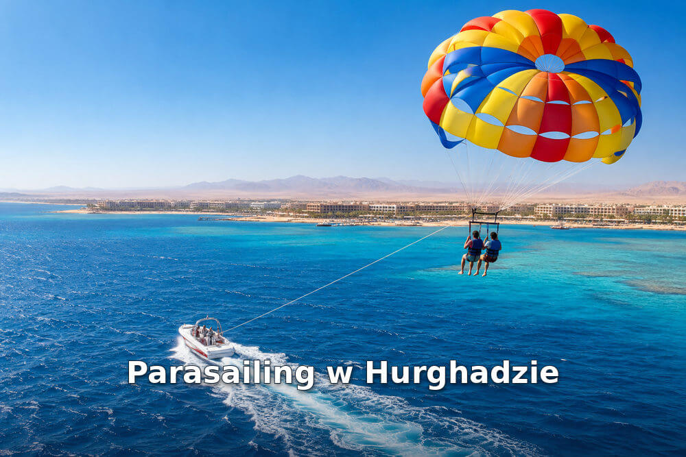 Dwie osoby pod kolorową czaszą parasailingową nad Morzem Czerwonym, holowane przez motorówkę na tle wybrzeża